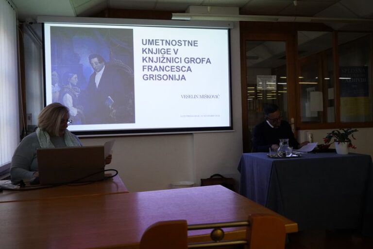 Na sliki je gospa, ki sedi in govori